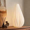 Fluted ceramic table lamp lit on wood console table