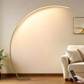 Sculptural brass arc floor lamp styled beside a sofa