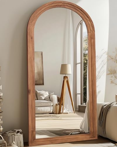 Arched wood floor mirror styled in a bedroom