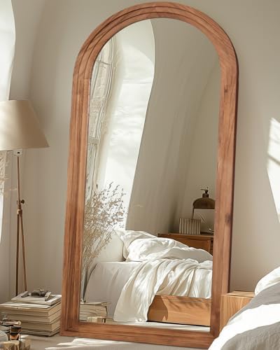 Arched wood floor mirror leaning against wall