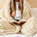 Chunky knit throw blanket draped over person reading