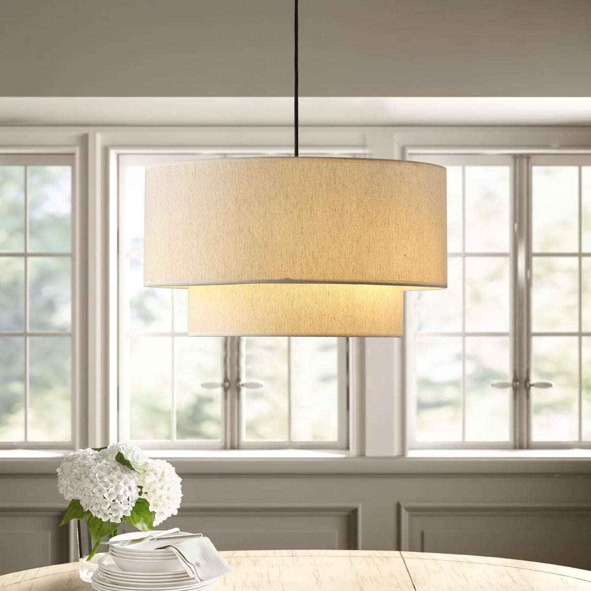 Two-tier linen drum pendant light over a round dining table