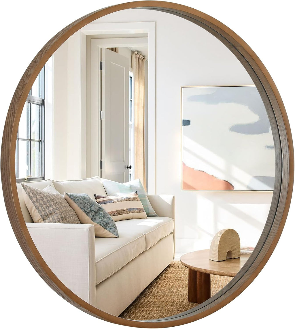 Round natural wood framed wall mirror reflecting a bright living room