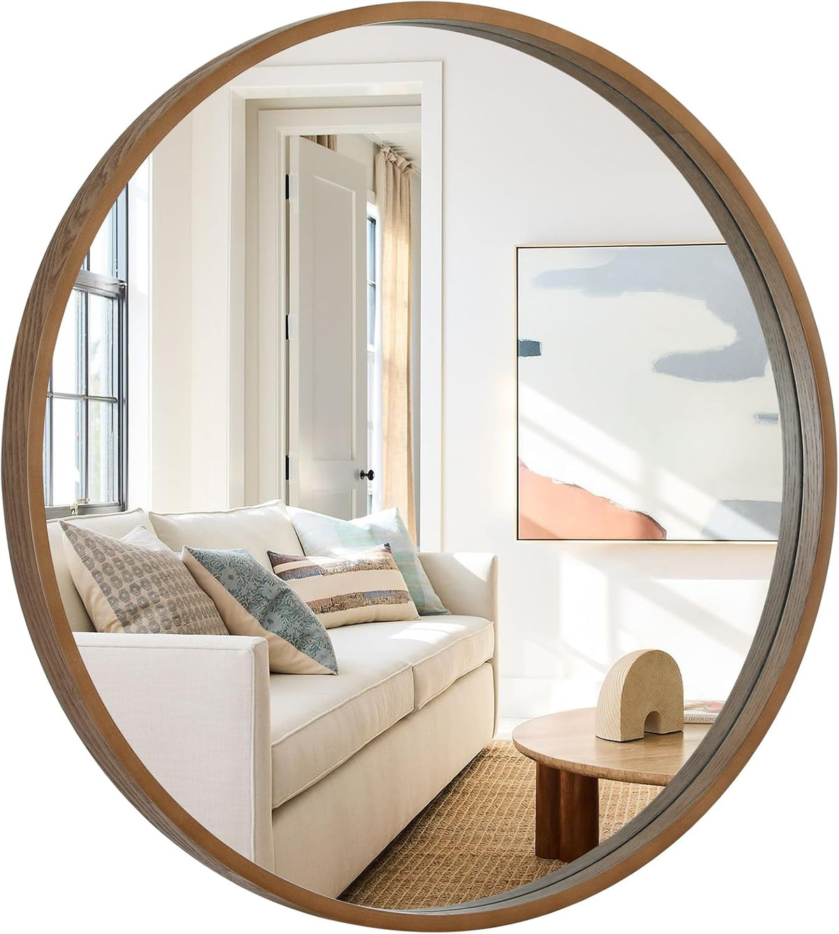 Round natural wood framed wall mirror reflecting a bright living room
