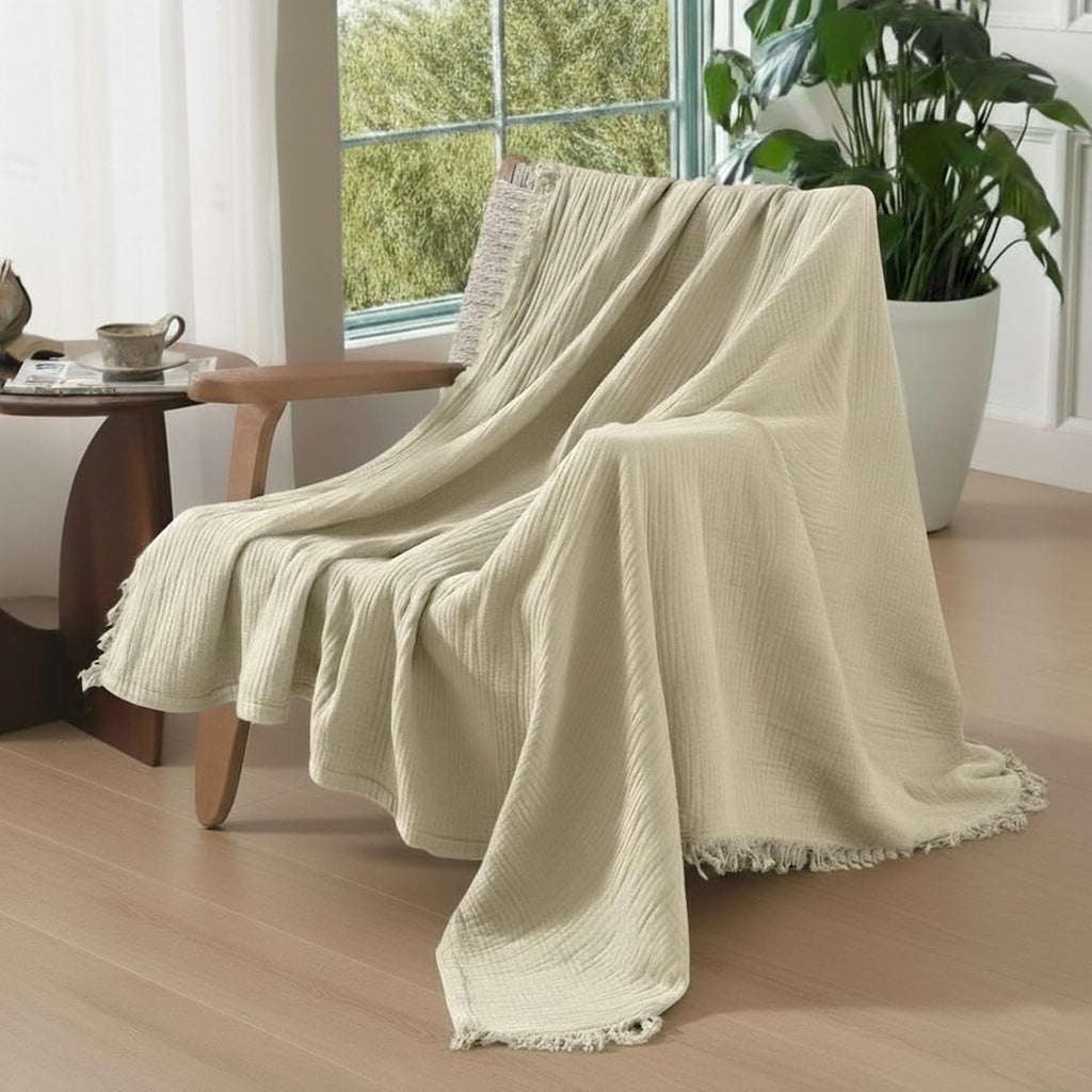 Oatmeal organic cotton muslin blanket draped over a neutral sofa