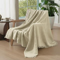 Oatmeal organic cotton muslin blanket draped over a neutral sofa