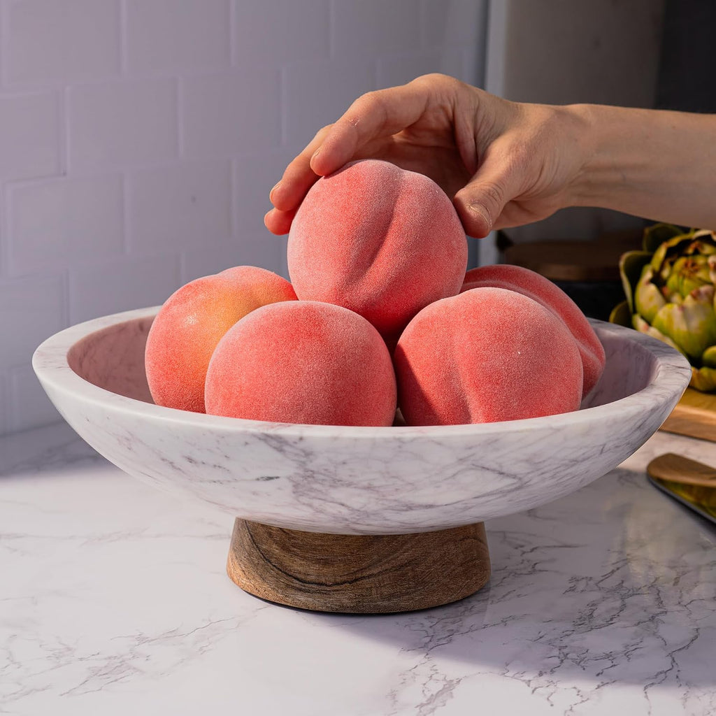 Marble pedestal bowl filled with peaches on a kitchen counter