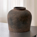 Aged brown earthenware vessel vase on a dark table