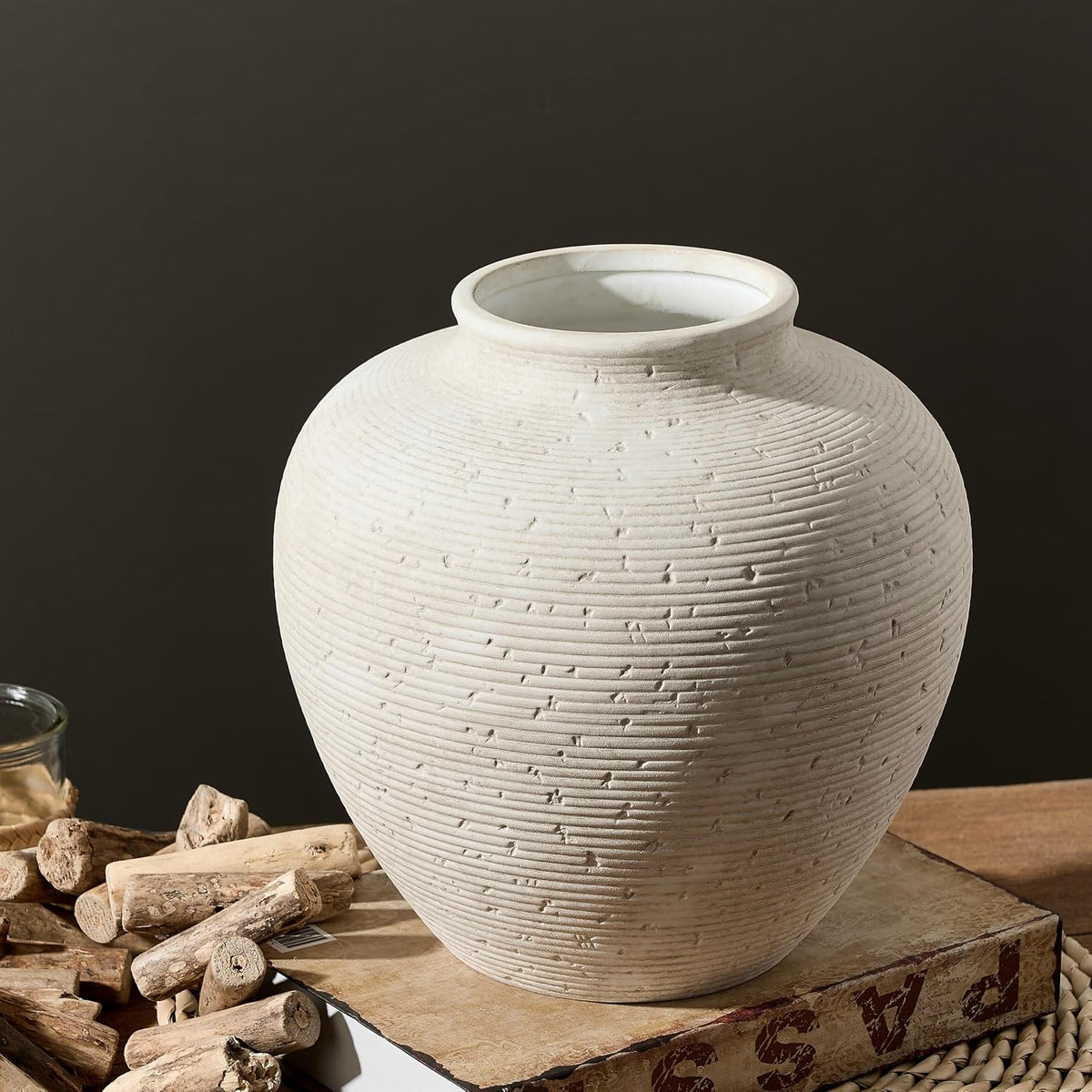 Round ceramic vase with combed texture on a wood surface